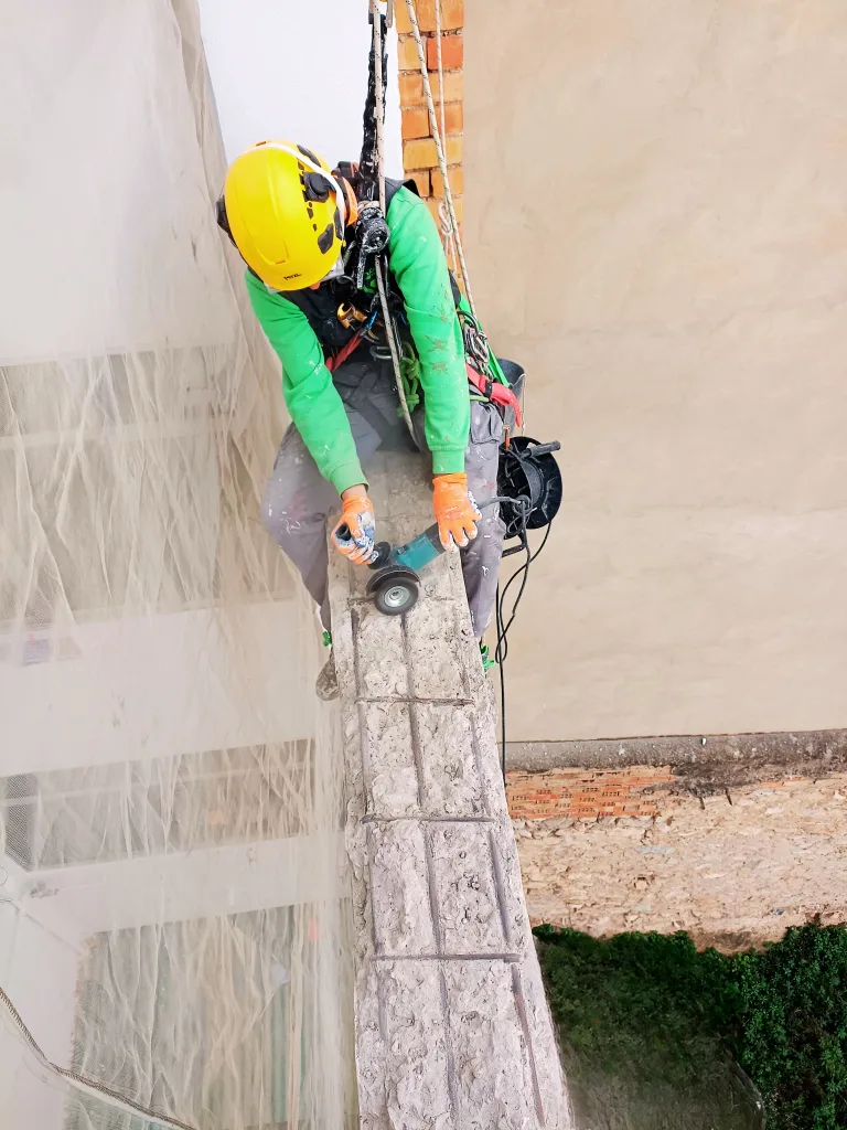 Trabajos verticales en Alicante. Operario de Verticales y Servicios reparando zuncho de atado en patio de luces
