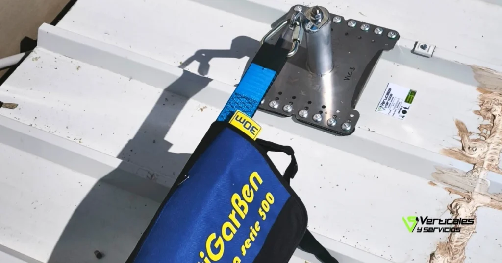 Detalle de un punto de anclaje fijo sobre cubierta metálica conectado a un absorbedor de energía para protección contra caídas.